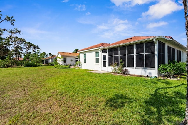 4378 Summertree Rd, Venice, FL 34293 - rear view of property featuring a sunroom, a lawn, a tiled roof, and stucco siding