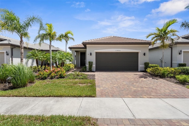 13486 Nobilio St, Venice, FL 34293 - mediterranean / spanish-style house featuring an attached garage, stucco siding, decorative driveway, and a tiled roof