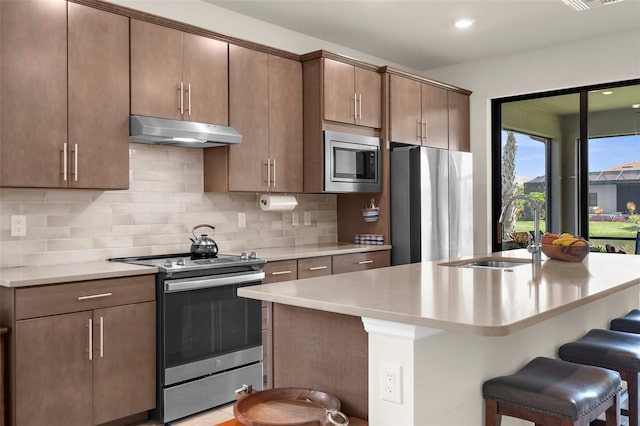13486 Nobilio St, Venice, FL 34293 - kitchen featuring stainless steel appliances, under cabinet range hood, light countertops, a breakfast bar, and recessed lighting