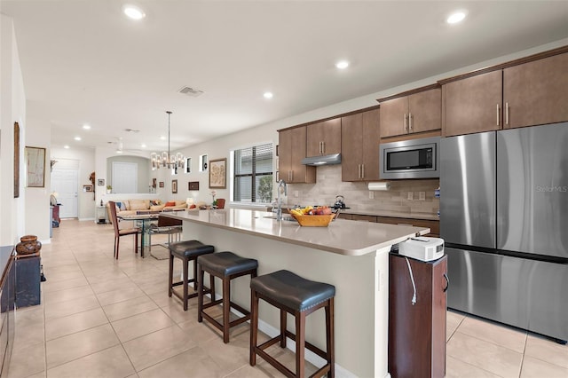 13486 Nobilio St, Venice, FL 34293 - kitchen featuring stainless steel appliances, tasteful backsplash, light countertops, a kitchen breakfast bar, and light tile patterned flooring