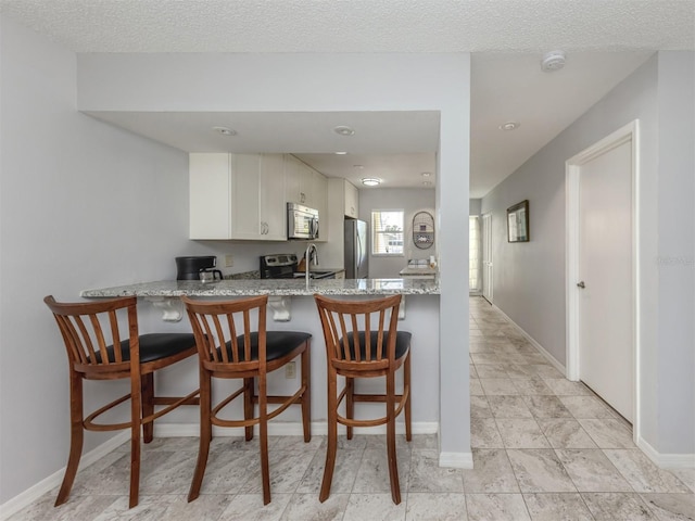 418 Cerromar Ct Unit 158, Venice, FL 34293 - kitchen with appliances with stainless steel finishes, baseboards, light stone countertops, a peninsula, and recessed lighting