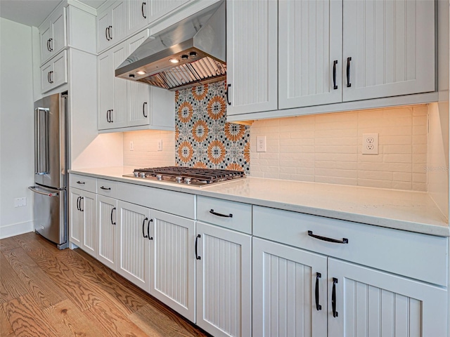 12705 Pinnacle Ln, Venice, FL 34293 - kitchen featuring exhaust hood, stainless steel appliances, tasteful backsplash, light wood-style floors, and white cabinetry