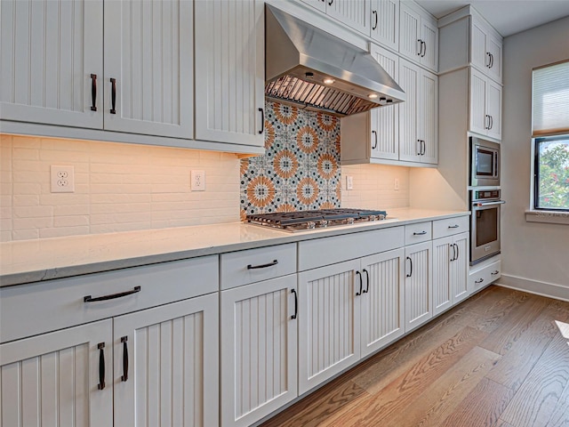 12705 Pinnacle Ln, Venice, FL 34293 - kitchen featuring under cabinet range hood, appliances with stainless steel finishes, light wood-style flooring, backsplash, and baseboards