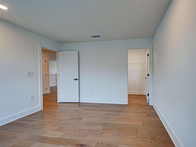 12705 Pinnacle Ln, Venice, FL 34293 - unfurnished bedroom with light wood-type flooring, baseboards, a walk in closet, a closet, and recessed lighting