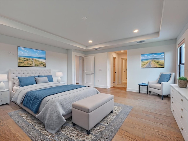 12705 Pinnacle Ln, Venice, FL 34293 - bedroom with a tray ceiling, light wood finished floors, baseboards, and recessed lighting