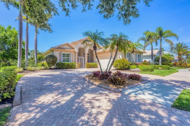 5018 Bella Terra Dr, Venice, FL 34293 - mediterranean / spanish house featuring stucco siding, curved driveway, and an attached garage