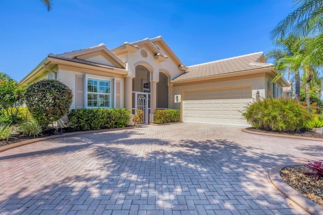 5018 Bella Terra Dr, Venice, FL 34293 - mediterranean / spanish home with stucco siding, an attached garage, and decorative driveway