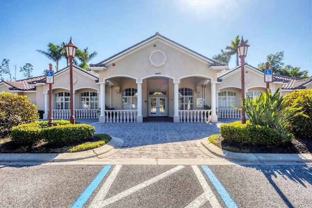 5018 Bella Terra Dr, Venice, FL 34293 - view of front of house with french doors, covered porch, stucco siding, and uncovered parking