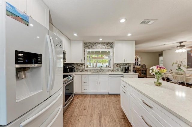 5207 5th Avenue Dr NW, Bradenton, FL 34209 - kitchen with stainless steel appliances, a sink, light wood finished floors, white cabinetry, and light countertops