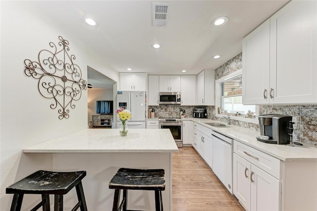 5207 5th Avenue Dr NW, Bradenton, FL 34209 - kitchen featuring appliances with stainless steel finishes, a kitchen breakfast bar, a sink, a peninsula, and white cabinets