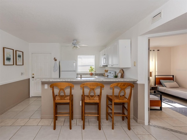 25050 Sandhill Blvd Unit 6A3, Punta Gorda, FL 33983 - kitchen featuring white appliances, a peninsula, white cabinets, a ceiling fan, and light tile patterned floors