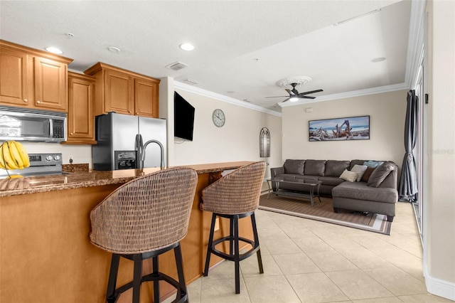 235 Base Ave E Unit 207, Venice, FL 34285 - kitchen featuring stainless steel appliances, ornamental molding, a kitchen breakfast bar, a ceiling fan, and light tile patterned floors