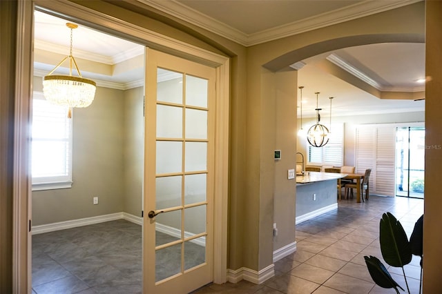 136 Positano Trl, Nokomis, FL 34275 - hall featuring a chandelier, a raised ceiling, arched walkways, crown molding, and baseboards