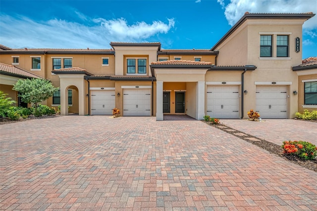 10213 Staggerbush Dr Unit 202, Venice, FL 34293 - view of property featuring an attached garage, driveway, stucco siding, and a tiled roof