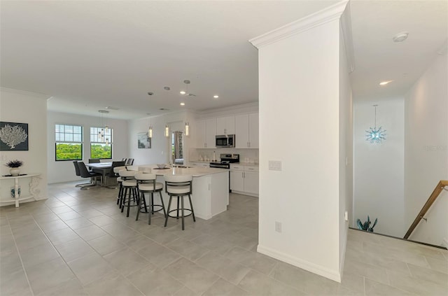 10213 Staggerbush Dr Unit 202, Venice, FL 34293 - kitchen featuring stainless steel appliances, a breakfast bar, an island with sink, white cabinetry, and light countertops