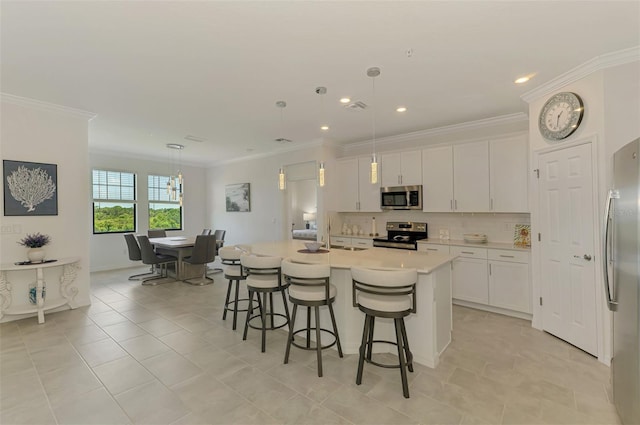 10213 Staggerbush Dr Unit 202, Venice, FL 34293 - kitchen featuring appliances with stainless steel finishes, crown molding, white cabinets, a kitchen bar, and an island with sink