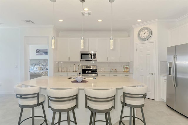 10213 Staggerbush Dr Unit 202, Venice, FL 34293 - kitchen featuring stainless steel appliances, a sink, white cabinets, decorative backsplash, and a center island with sink