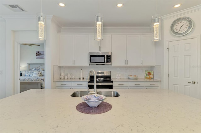 10213 Staggerbush Dr Unit 202, Venice, FL 34293 - kitchen featuring appliances with stainless steel finishes, white cabinets, light stone countertops, pendant lighting, and tasteful backsplash