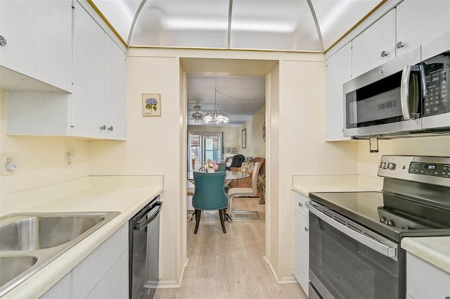 708 Tamiami Trl S Unit 115, Venice, FL 34285 - kitchen featuring stainless steel appliances, light wood finished floors, white cabinetry, light countertops, and a chandelier