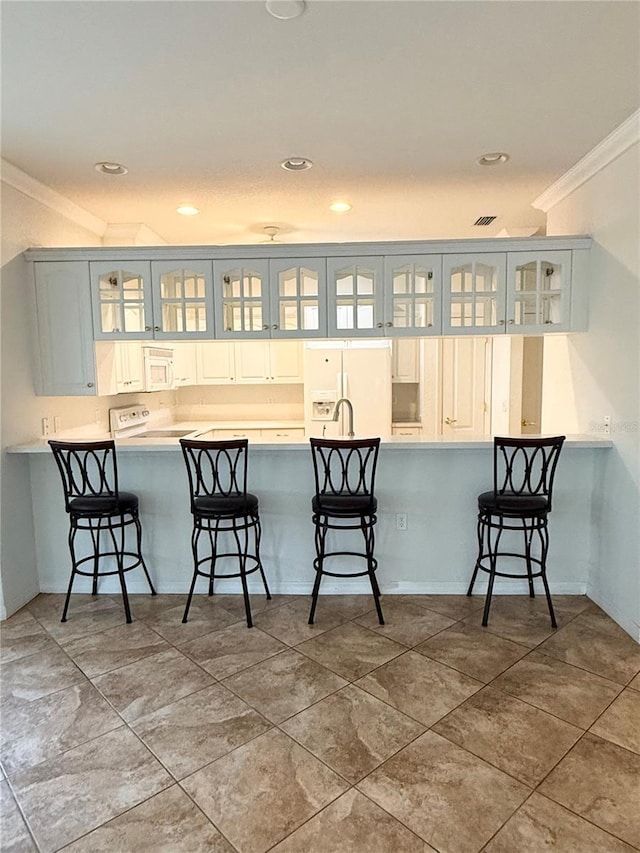 3790 Cadbury Cir Unit 40, Venice, FL 34293 - kitchen featuring ornamental molding, white appliances, a peninsula, a breakfast bar, and glass insert cabinets
