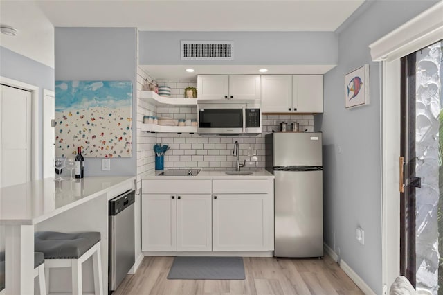 1555 Tarpon Center Dr Unit G 235, Venice, FL 34285 - kitchen with stainless steel appliances, open shelves, tasteful backsplash, white cabinets, and light wood-type flooring
