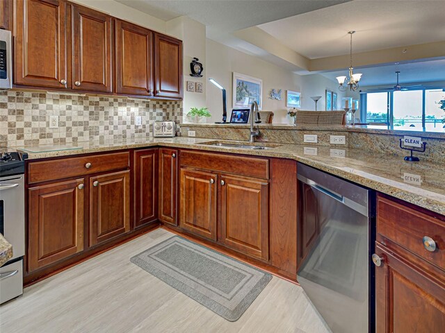 516 Tamiami Trl S Unit 303, Nokomis, FL 34275 - kitchen with appliances with stainless steel finishes, light wood-style flooring, decorative backsplash, and light stone counters