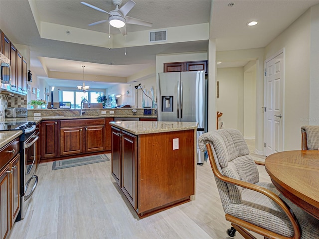 516 Tamiami Trl S Unit 303, Nokomis, FL 34275 - kitchen with stainless steel appliances, a raised ceiling, light wood-type flooring, a peninsula, and a kitchen island