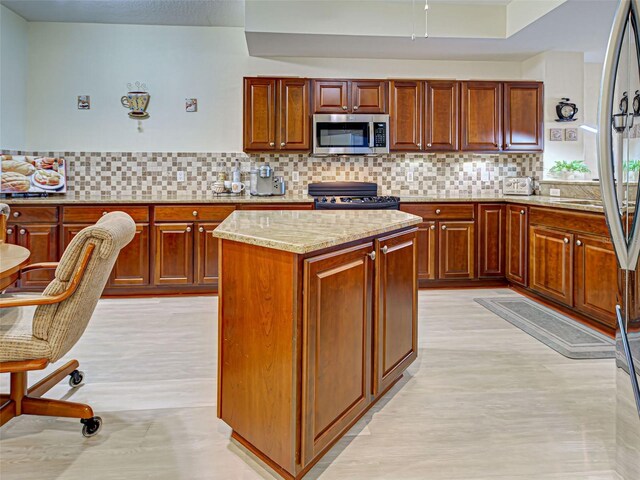 516 Tamiami Trl S Unit 303, Nokomis, FL 34275 - kitchen with stainless steel microwave, electric range, light stone counters, and decorative backsplash