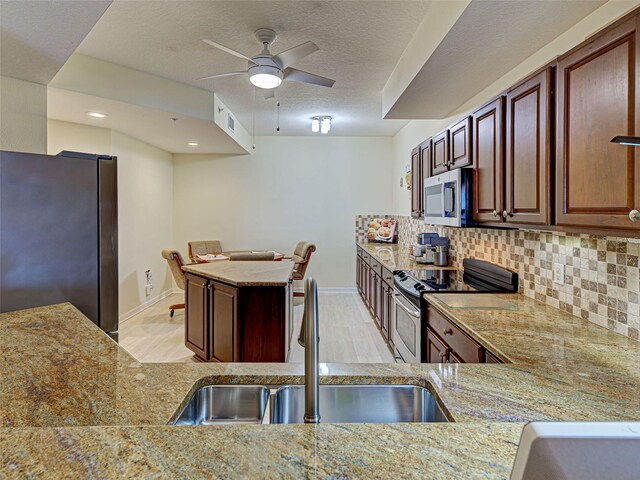 516 Tamiami Trl S Unit 303, Nokomis, FL 34275 - kitchen with stainless steel appliances, a ceiling fan, backsplash, light wood-style flooring, and a textured ceiling