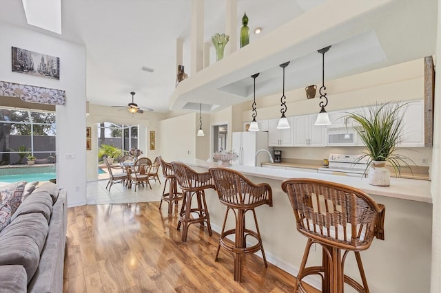 188 Grand Oak Cir, Venice, FL 34292 - kitchen featuring white appliances, a breakfast bar, open floor plan, light countertops, and a towering ceiling