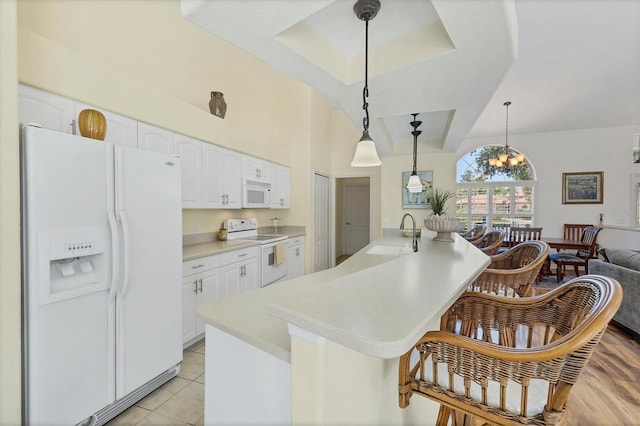 188 Grand Oak Cir, Venice, FL 34292 - kitchen featuring white appliances, a raised ceiling, a kitchen bar, white cabinetry, and light countertops