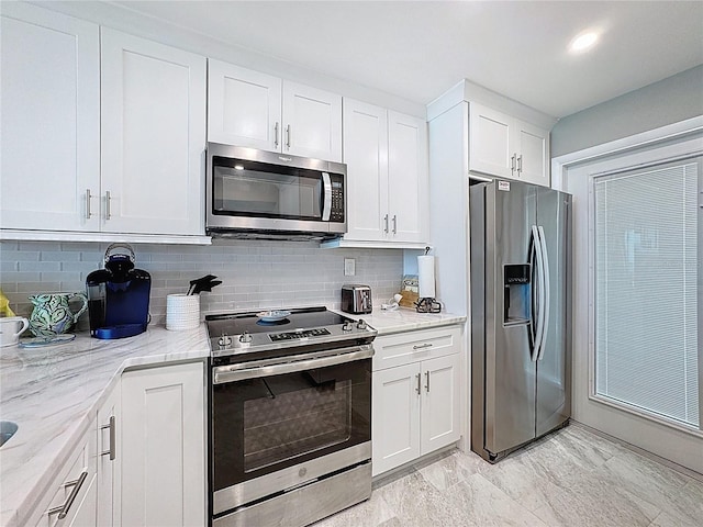 1100 Tarpon Center Dr Unit 503-5C, Venice, FL 34285 - kitchen with stainless steel appliances, backsplash, white cabinets, and light stone countertops