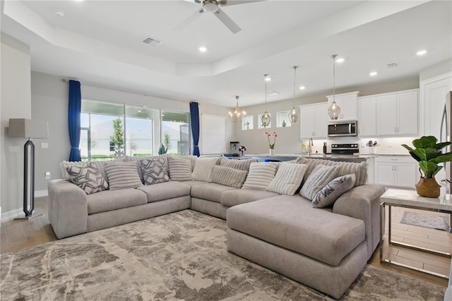 15963 Crofton Springs Way, Port Charlotte, FL 33953 - living room featuring light wood-style flooring, recessed lighting, ceiling fan, a tray ceiling, and baseboards