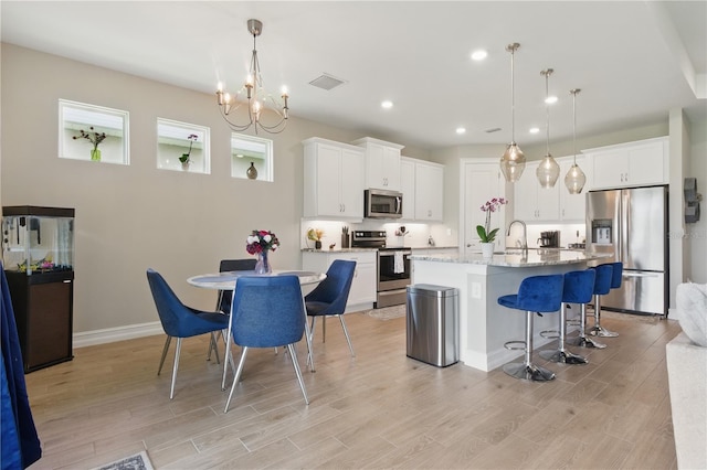 15963 Crofton Springs Way, Port Charlotte, FL 33953 - kitchen featuring appliances with stainless steel finishes, a kitchen breakfast bar, light wood finished floors, white cabinetry, and recessed lighting
