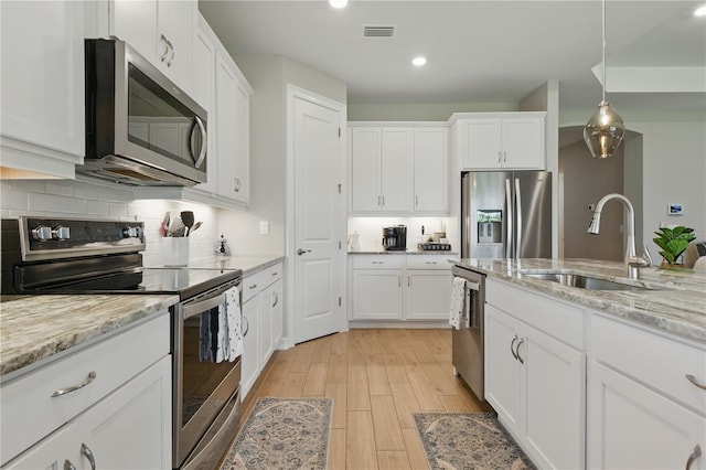 15963 Crofton Springs Way, Port Charlotte, FL 33953 - kitchen featuring appliances with stainless steel finishes, a sink, light wood-style floors, white cabinets, and backsplash