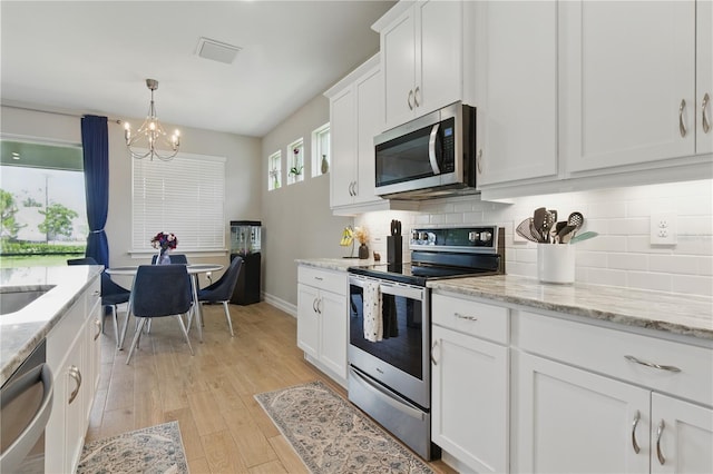 15963 Crofton Springs Way, Port Charlotte, FL 33953 - kitchen featuring appliances with stainless steel finishes, a chandelier, tasteful backsplash, and light wood-type flooring