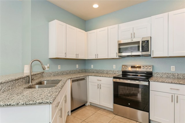 11954 Tempest Harbor Loop, Venice, FL 34292 - kitchen with appliances with stainless steel finishes, light tile patterned floors, a peninsula, white cabinets, and light stone countertops