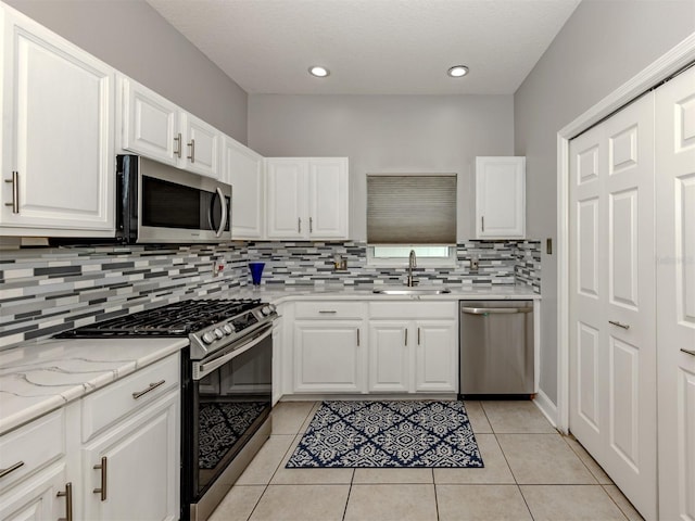 6505 Meandering Way, Lakewood Ranch, FL 34202 - kitchen with appliances with stainless steel finishes, decorative backsplash, white cabinetry, light tile patterned flooring, and recessed lighting
