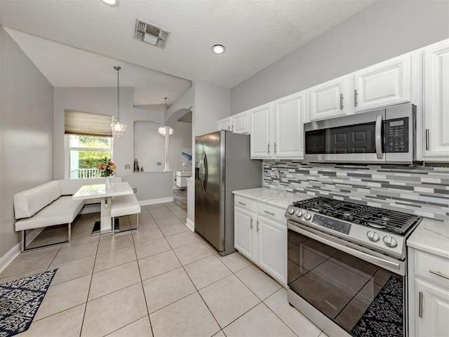 6505 Meandering Way, Lakewood Ranch, FL 34202 - kitchen with appliances with stainless steel finishes, backsplash, arched walkways, white cabinets, and vaulted ceiling