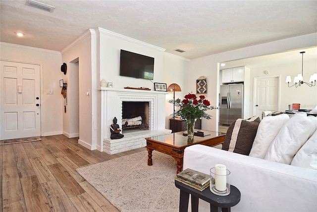 3340 Webber St, Sarasota, FL 34239 - living room with light wood-style floors, crown molding, a chandelier, a textured ceiling, and a fireplace