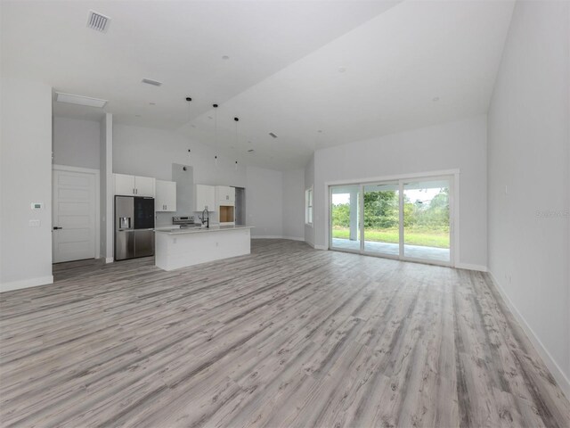 137 Mariner Ln, Rotonda West, FL 33947 - unfurnished living room with high vaulted ceiling, light wood-style floors, baseboards, and a sink
