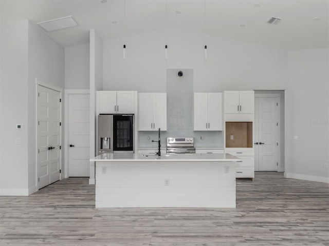 137 Mariner Ln, Rotonda West, FL 33947 - kitchen featuring stainless steel appliances, high vaulted ceiling, an island with sink, white cabinets, and light wood-style floors