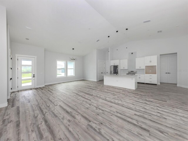 137 Mariner Ln, Rotonda West, FL 33947 - unfurnished living room featuring light wood-style flooring, baseboards, and high vaulted ceiling