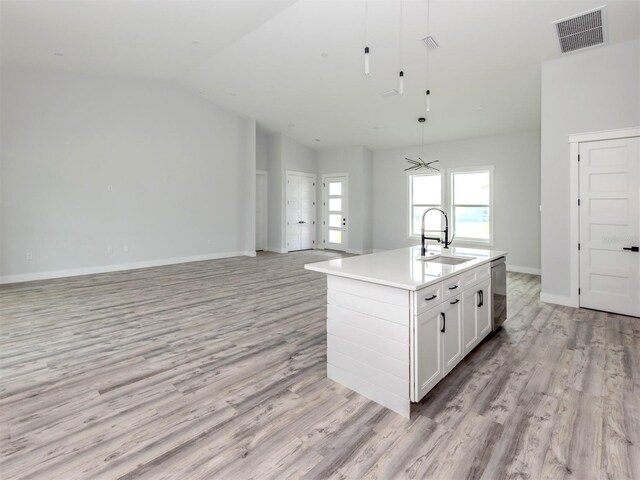137 Mariner Ln, Rotonda West, FL 33947 - kitchen featuring a sink, stainless steel dishwasher, light wood finished floors, white cabinetry, and lofted ceiling