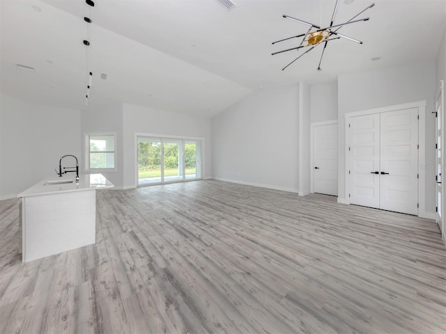 137 Mariner Ln, Rotonda West, FL 33947 - unfurnished living room with light wood-type flooring, vaulted ceiling, a chandelier, and baseboards