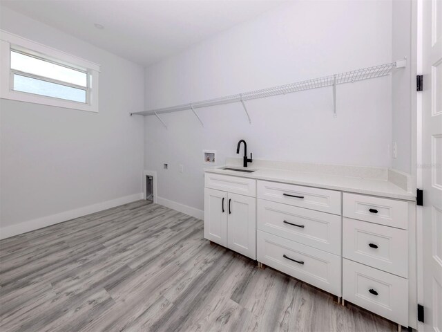 137 Mariner Ln, Rotonda West, FL 33947 - laundry area with washer hookup, cabinet space, electric dryer hookup, light wood finished floors, and baseboards
