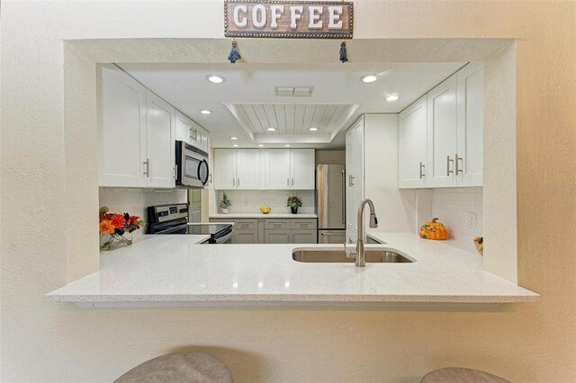 2718 Orchid Oaks Dr Unit C-202, Sarasota, FL 34239 - kitchen featuring stainless steel appliances, decorative backsplash, recessed lighting, light stone counters, and a textured wall