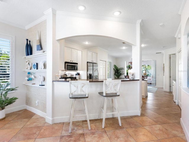 1164 Beachcomber Ct Unit 19, Osprey, FL 34229 - kitchen featuring stainless steel appliances, arched walkways, a peninsula, dark countertops, and a kitchen bar