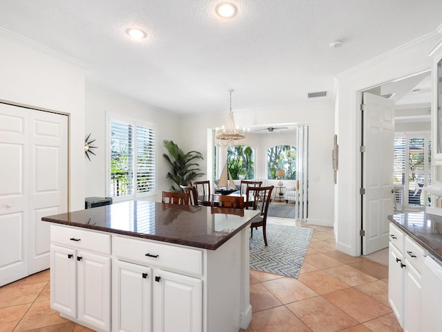 1164 Beachcomber Ct Unit 19, Osprey, FL 34229 - kitchen with ornamental molding, a kitchen island, white cabinets, decorative light fixtures, and light tile patterned flooring