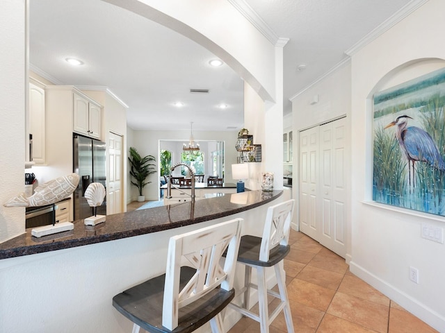 1164 Beachcomber Ct Unit 19, Osprey, FL 34229 - kitchen with stainless steel fridge with ice dispenser, a peninsula, crown molding, dark stone counters, and a kitchen bar